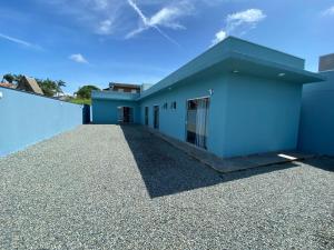 a blue house with a gravel driveway at Suíte 3 Praia do Grant in Barra Velha