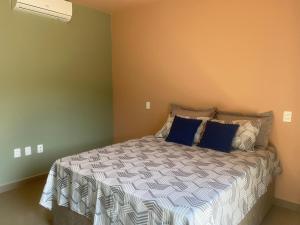 a bedroom with a large bed with blue pillows at Suíte 3 Praia do Grant in Barra Velha