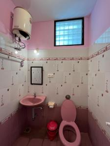 Baño rosa con aseo rosa y lavabo en Paris Apartment, en Pondicherry