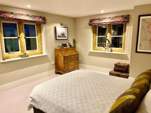 a bedroom with a bed and two windows at Everdon Hill House - B&B in Great Everdon