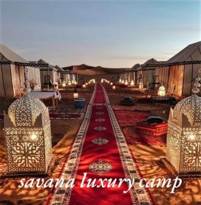 a room with a red carpet and some tents at Savanna dunes luxury camp in Merzouga