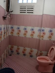 a bathroom with a pink toilet and flowers on the wall at Rimadi Lake Guest Inn in Eravur