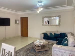 a living room with a blue couch and a tv at Lovely 3-Bedroom Rental Unit with Pool in Sheikh Zayed