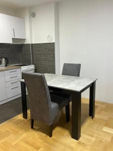 a dining table and two chairs in a kitchen at Apartman Moskva in Teslić