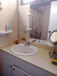 eine Badezimmerablage mit Waschbecken und Spiegel in der Unterkunft Apto en Porlamar - Nueva esparta, a 5 min de playa Concorde in Porlamar