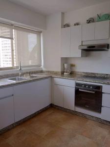 eine Küche mit weißen Schränken und einer Spüle und einem Herd in der Unterkunft Apto en Porlamar - Nueva esparta, a 5 min de playa Concorde in Porlamar