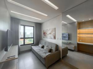 a living room with a couch and a television at Lindo Flat Planejado com Vista Para Cidade in Campo Grande