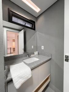 a bathroom with a sink and a mirror at Lindo Flat Planejado com Vista Para Cidade in Campo Grande