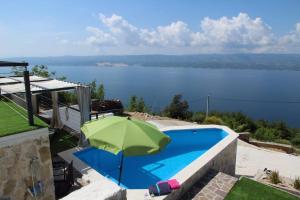 a green umbrella sitting next to a swimming pool at Mountain Stone Villa with pool in Stanići