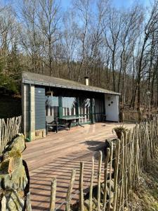 a small building with a wooden deck next to a fence at La Colline Stavelot in Stavelot
