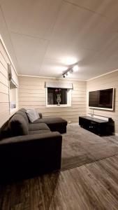 a living room with a couch and a flat screen tv at Rancho Apartment in Langevåg in Sula