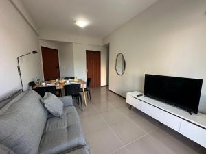 Una sala de estar con un sofá y un televisor de pantalla plana. en Ap a alguns passos da praia do Bosque | ROGR104, en Rio das Ostras