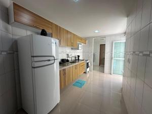Una cocina con refrigerador blanco y gabinetes de madera. en Ap a alguns passos da praia do Bosque | ROGR104, en Rio das Ostras