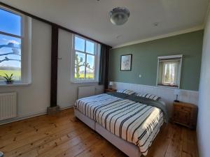 a bedroom with a bed and two windows at Appartement Het Voorhuis in Horssen