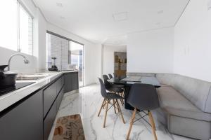a kitchen and living room with a couch and a table at Cobertura a beira mar com piscina e churrasqueira in Praia Grande
