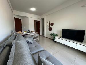 a living room with a couch and a tv at Ap a alguns passos da praia do Bosque | ROGR207 in Rio das Ostras