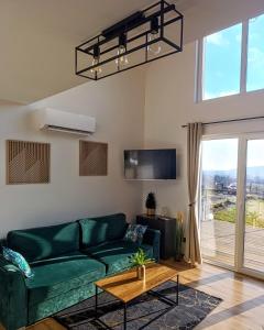 a living room with a green couch and a large window at Domek Na Wądołach in Jedlicze