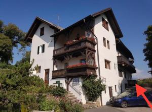 a white building with a balcony and a blue car at Apartment Maximilian in Völs am Schlern