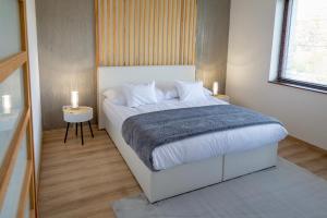 a bedroom with a white bed with a blue blanket at Alsóerdő Villa Resort in Zalaegerszeg