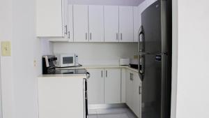 a kitchen with white cabinets and a black refrigerator at Arecibo Hotel 2104 in Arecibo