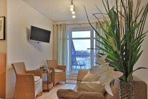 un salon avec un canapé et un vase avec une fleur dans l'établissement Residenz Haffblick Wohnung 31, à Boltenhagen