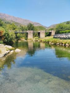 a river with a bridge in the background at Piscinas, Serra da Estrela AL in Bouça +17 photos