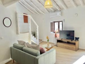 a living room with a couch and a flat screen tv at Casa Salome, Alojamiento con terraza y vistas al valle in Benadalid