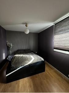 a black bedroom with a bed and a window at Koselig leilighet in Stavanger
