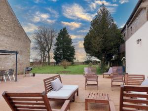 a patio with wooden chairs and a grill and trees at Gite Etoile du berger in Ouarville