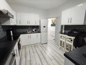a kitchen with white cabinets and a wooden floor at New Guest House, Individual Ensuite Rooms with Comfortable Double Beds, TV and WiFi in Luton