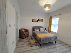 a bedroom with a bed and a chair and a window at New Guest House, Individual Ensuite Rooms with Comfortable Double Beds, TV and WiFi in Luton