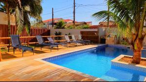 a pool with chairs and a palm tree in a yard at Mar Egeu Arte & Pouso in Peruíbe