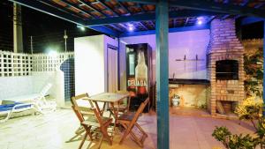 a patio with a table and a stone fireplace at Casa da Nina | Beira-mar in Tamandaré