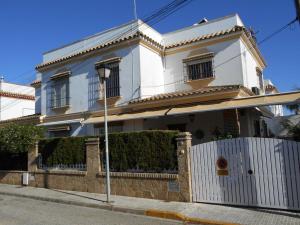a white house with a fence in front of it at Apartamento Caracola Comfortable holiday residence in Chipiona