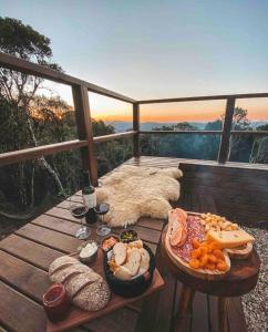 a picnic table with food and wine on a balcony at Quinta Alta Vista - Cabana Xaxim com jacuzzi e vista incrível in Rancho Queimado
