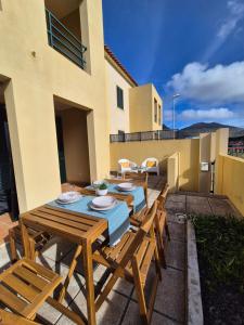 eine Terrasse mit Holztischen und -stühlen sowie ein Gebäude in der Unterkunft Cantinho do Porto Santo in Porto Santo