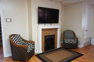 a living room with two chairs and a fireplace with a tv at Chic Midtown 6BR Main house and 3BR Cottage in Memphis