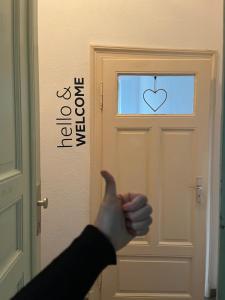 eine Person, die auf eine Tür mit Herz zeigt in der Unterkunft hello&welcome Dresden City-Apartment in Dresden