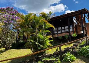 ein Haus mit einem Zaun und einigen Palmen in der Unterkunft Pousada Colar de Ouro Chalés in Cunha