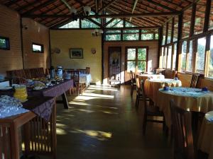 ein Esszimmer mit Tischen und Stühlen und Fenstern in der Unterkunft Pousada Colar de Ouro Chalés in Cunha