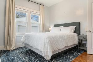 a white bedroom with a bed and a window at Benson's Cozy 3-BR Retreat with BBQ Grill in Omaha
