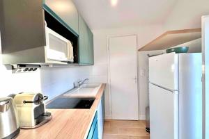 a kitchen with a white refrigerator and a sink at Studio rénové et fonctionnel in Bron
