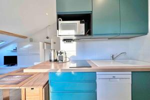 a kitchen with blue cabinets and a microwave at Studio rénové et fonctionnel in Bron