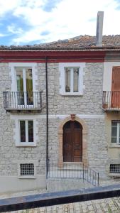 a stone house with a wooden door and two balconies at GuestHouse Affittacamere Padre Pio MORCONE CENTRO in Morcone