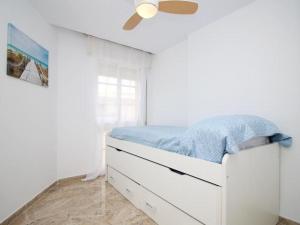 Un dormitorio blanco con una cama y un ventilador de techo. en Rincón del Mar, en Rincón de la Victoria