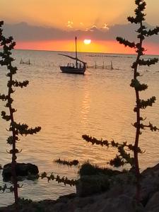 a boat on the water at sunset with trees at Casa loud in Sidi el Moujahed