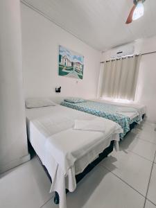 two beds in a white room with a window at Pousada Rio do Prado in Porto Seguro +28 photos