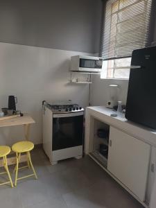 a small kitchen with a stove and a table and stool at Loft Ouro Fino in Belo Horizonte