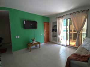 a living room with a green wall and a tv at Dreimar Hotel Boutique in Cartagena de Indias