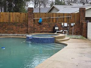 ein Swimmingpool in einem Hinterhof mit einem Ziegelzaun in der Unterkunft Luxury Southern Mansion w/ Pool in Memphis